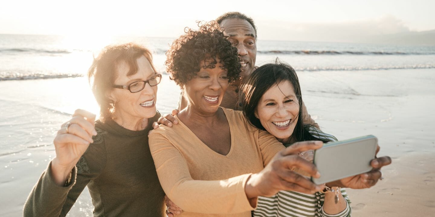 a group of senior people taking a selfie on the beach