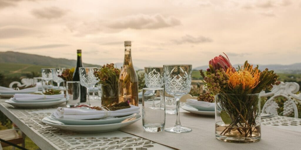 a table set for a dinner party with wine glasses, plates, and a vase of flowers