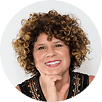 Denise Pane portrait - with her curly brown hair, black sleeveless blouse, hands on her chin and a smile