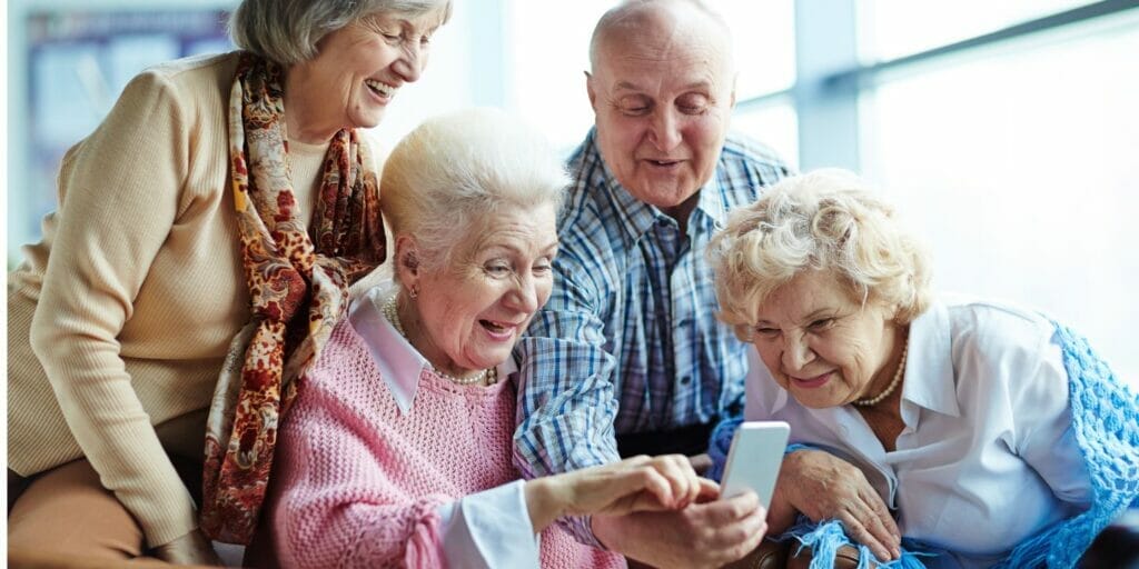 a group of elderly people sitting on a couch looking at a cell phone