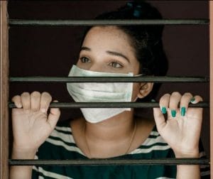 Female behind a gate wearing a face mask during a pandemic