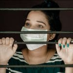 Female behind a gate wearing a face mask during a pandemic