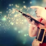 Santa Claus using a tablet, with sparkles emanating from it against a blue, festive background.