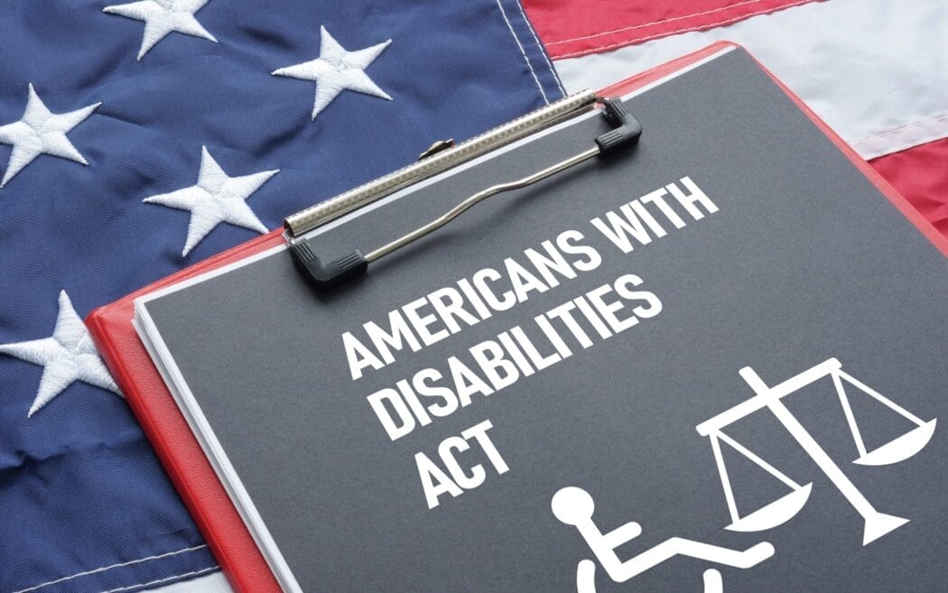 A clipboard reading “Americans with Disabilities Act” with wheelchair and scale icons on a US flag, symbolizing ADA Website Lawsuits.