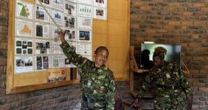 Two women from the The Black Mambas anti-poaching unit stand in front of graphs and charts showing their mission, their tactics, their challenges and their success rate.